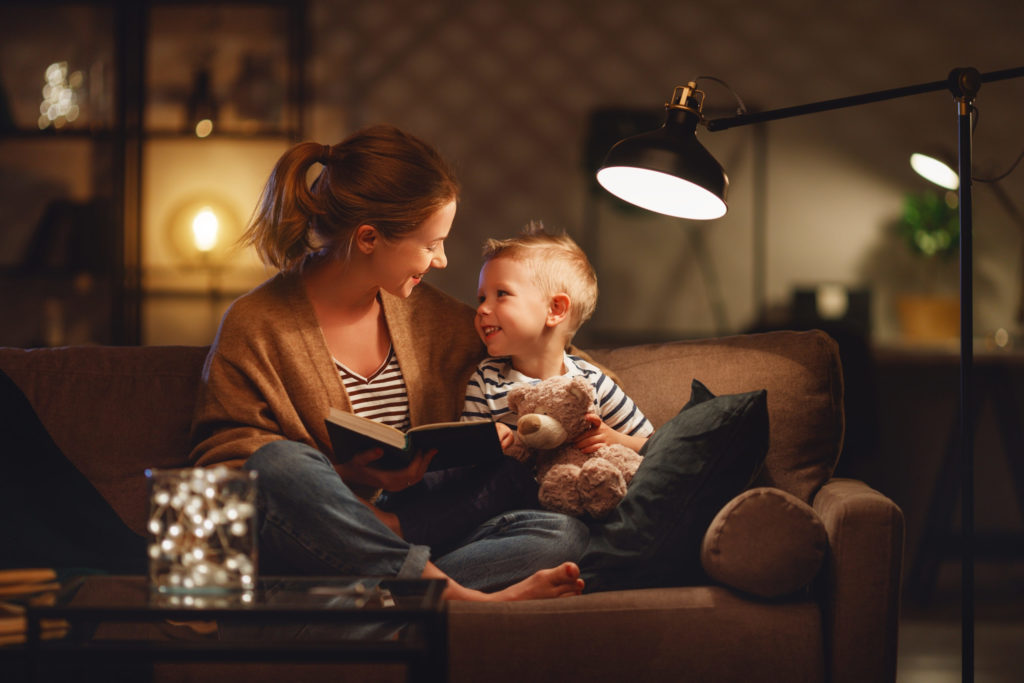 A woman with her son reading a book on the couch