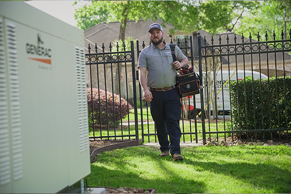 An employee carrying a tool kit walking outside to a generator