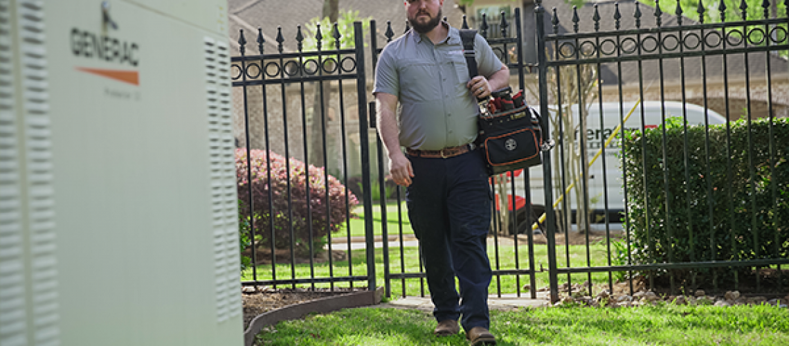 An employee carrying a tool kit walking outside to a generator